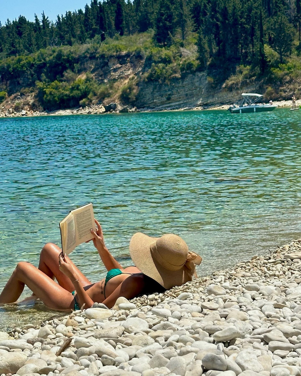 Η Νεφέλη Λιβιεράτου διαβάζει το βιβλίο της με τα κρυστάλλινα νερά του Ιονίου στο backround.